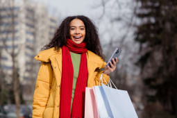 Une femme avec des sacs tient un tlphone.