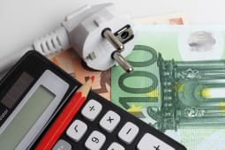 Une prise lectrique, un billet et une calculatrice.