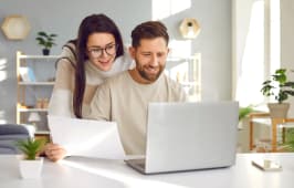 Un couple regarde son ordinateur l'air content.