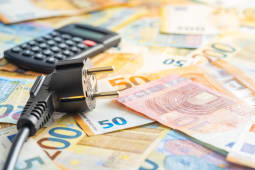 Des billets une calculatrice et une prise lectrique.