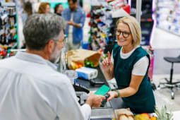 Une caissire fait payer un client dans un magasin.