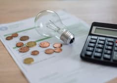 Une calculatrice, une ampoule, des pices de monnaie et une facture.