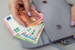 Quelqu'un range des billets dans un portefeuille.