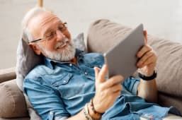 Une personne regarde une tablette en souriant.