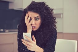 Une femme regarde son tlphone l'air surpris.