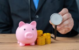 Une tirelire avec des piles de pices de monnaie et un stthoscope.