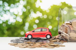 Une voiture miniature roule sur des pices de monnaie.