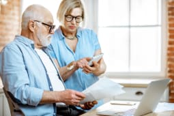 Un homme et une femme regardent des documents et une calculatrice