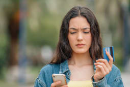 Une femme regarde sa carte bancaire et son tlphone.