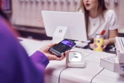 Une personne tend son tlphone pour payer.