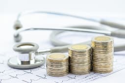 Des piles de pices de monnaie et un stthoscope.