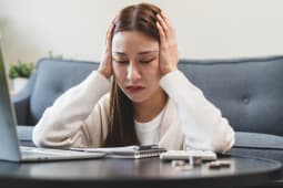 Une femme se prend la tte dans les mains en regardant des documents.