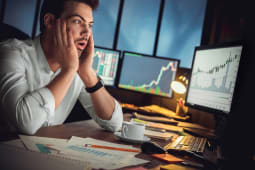 Un homme regarde des indicateurs boursiers l'air inquiet.