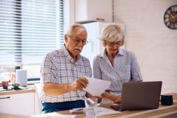 Un couple de personnes ges regardant un ordinateur.