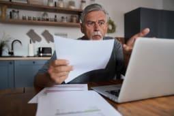 Un homme l'air choqu devant son ordinateur.