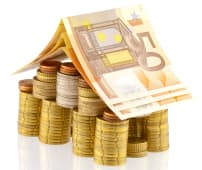 Une pile de pices et des billets, en forme de maison.