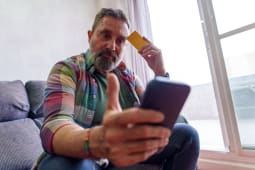 Un homme regarde son tlphone portable et sa carte bancaire.