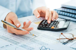 Une calculatrice, des lunettes et une pile de documents.