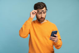 Un homme regarde son tlphone l'air surpris.