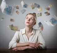 Une femme regarde des billets voler autour d'elle.