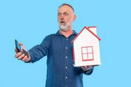 Un homme regarde une calculatrice l'air surpris. 