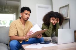 Deux personnes se questionnent devant des documents.