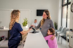 Une femme avec un enfant rgle une consultation chez un mdecin.