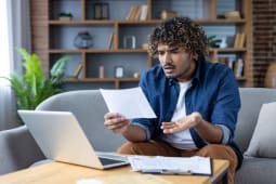 Un homme regarde son ordinateur en s'interrogeant.