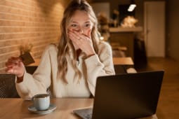 Une femme regarde son ordinateur avec sa carte bancaire l'air inquiet.