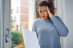 Une femme regarde un document en se tenant la tte.