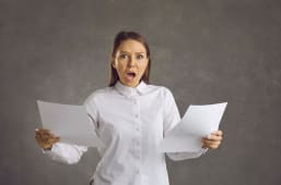 Une femme regarde des documents l'air surpris.