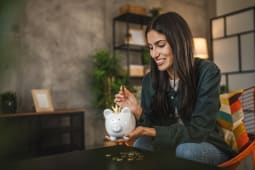 Une femme met de l'argent dans une tirelire.