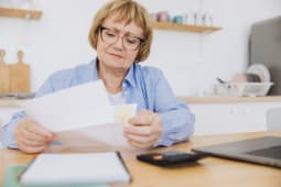Une femme regarde un document avec une calculatrice.