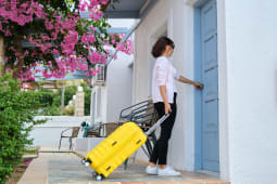 Une personne avec une valise ouvre la porte d'un logement.