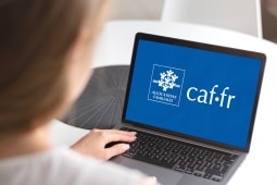 Une personne devant la page d'accueil de la CAF sur son ordinateur.