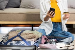 Une personne regarde sa carte bancaire, prs d'une valise.