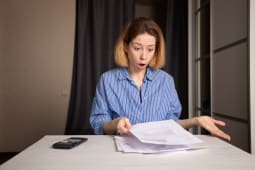 Une femme regarde un document l'air surpris.