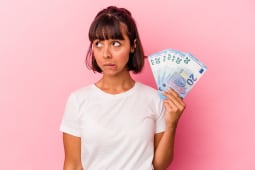 Une femme s'interroge avec de l'argent dans la main.