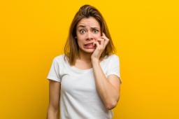 Jeune femme caucasienne naturelle se rongeant les ongles, nerveuse et