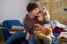 Femme et fille clinant avec un ours en peluche.