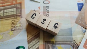 Des cubes en bois avec CSG sur des billets d'euro.