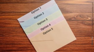 Enveloppes colores numrotes sur une table en bois.