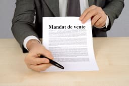 Homme en costume prsentant un document intitul Mandat de vente.