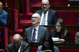 Hommes et femmes assis coutant attentivement dans une salle parlementaire. Roland LEscure