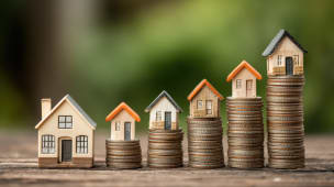 Maisons miniatures poses sur des piles croissantes de pices.