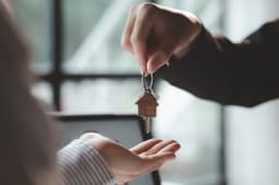 Remise de cls de maison entre deux personnes indoors.