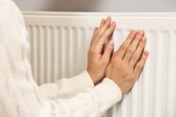 Une femme se rchauffant les mains prs du radiateur.