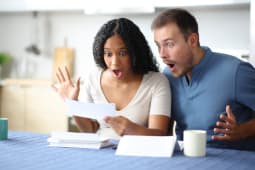 Un couple tonn lisant un relev bancaire dans la cuisine.