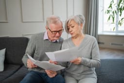 Couple g examinant des documents ensemble sur un canap.