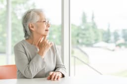 Femme �g�e r�fl�chit pr�s de la fen�tre lumineuse.